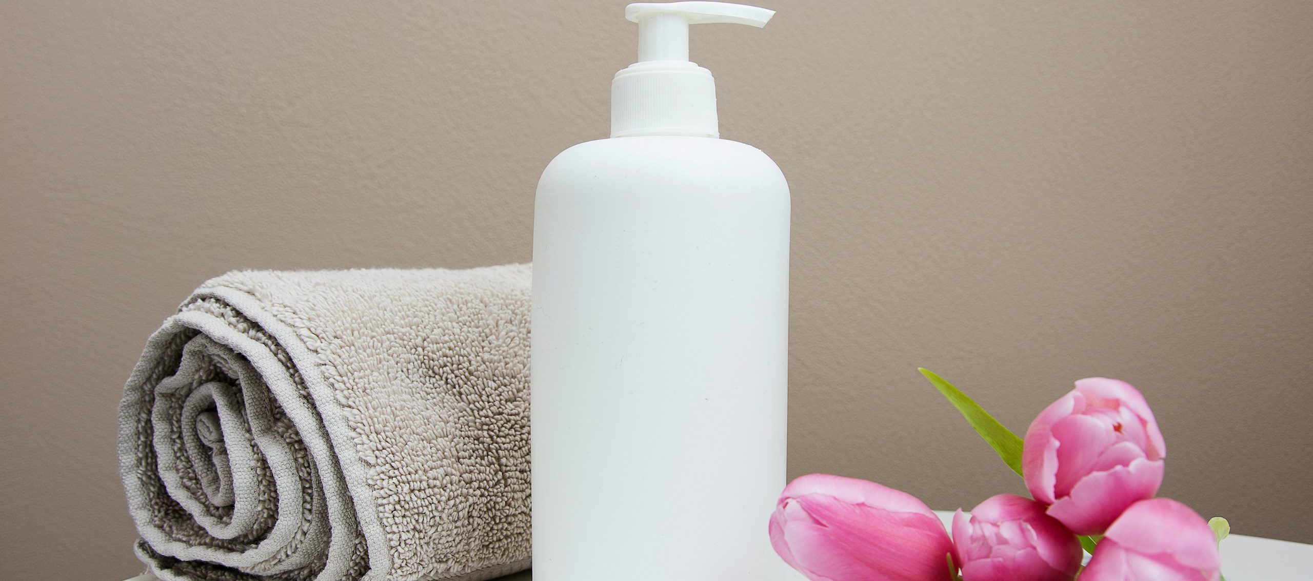 Handtuch, Massageöl und Blumen im Behandlungsraum von Relax & More